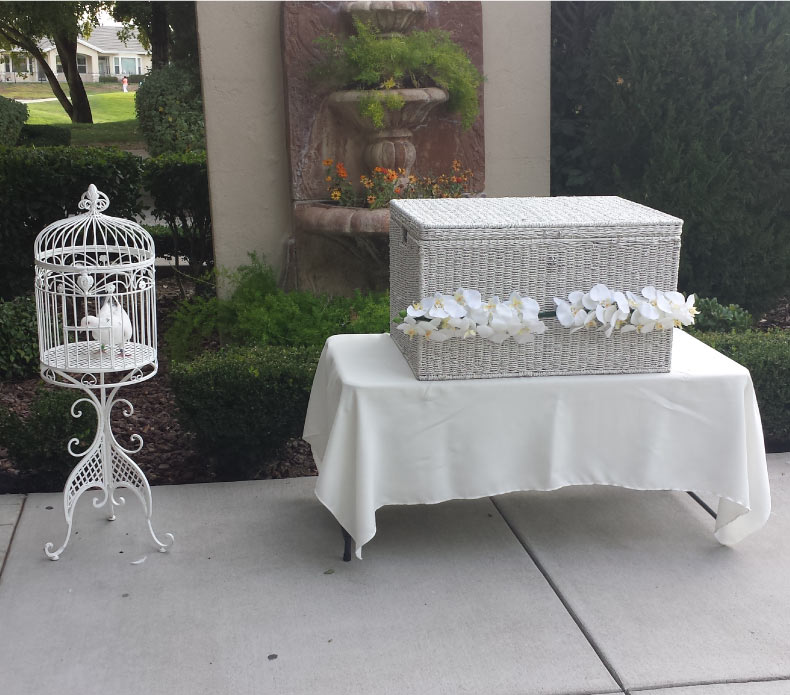 Elegant white wings dove release display featuring a release box and birdcage near a fountain for an outdoor funeral or special event in Tulare County